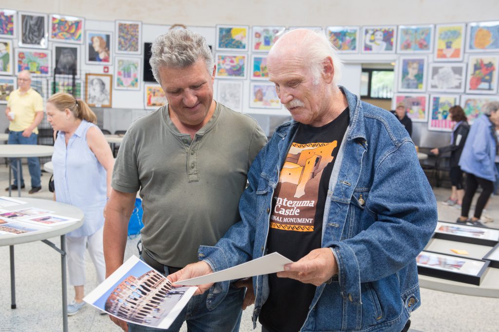 Image of two men looking at a photo of the Colosseum in Rome. 